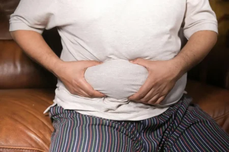 صورة رجل يمسك ببطنه لمقال "الترهل بعد التكميم"