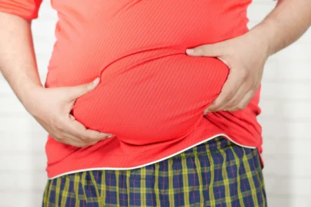 صورة رجل يمسك ببطنه لمقالة عن أضرار السمنة